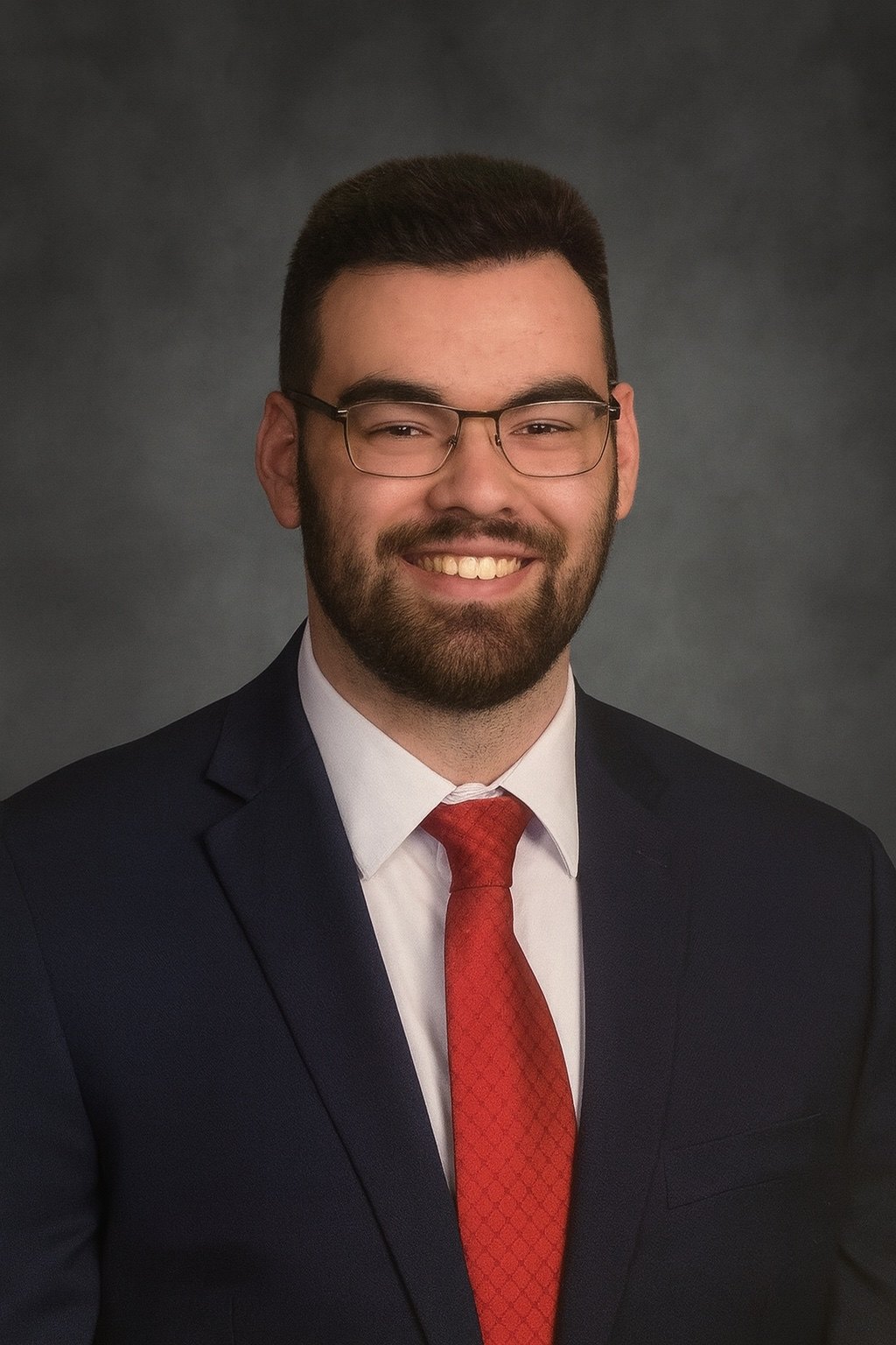 Bailey Forbes, smiling, in a navy suit and red tie